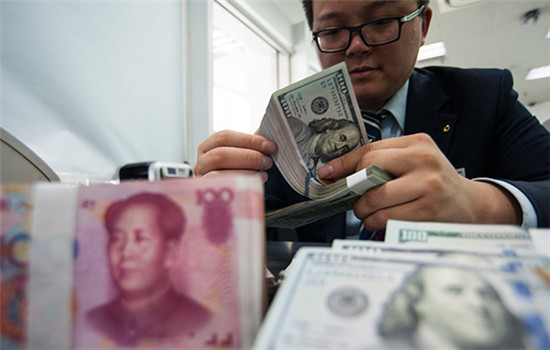 An employee at a bank counter in Nantong, Jiangsu province, counts renminbi and dollars. (Photo/China Daily)